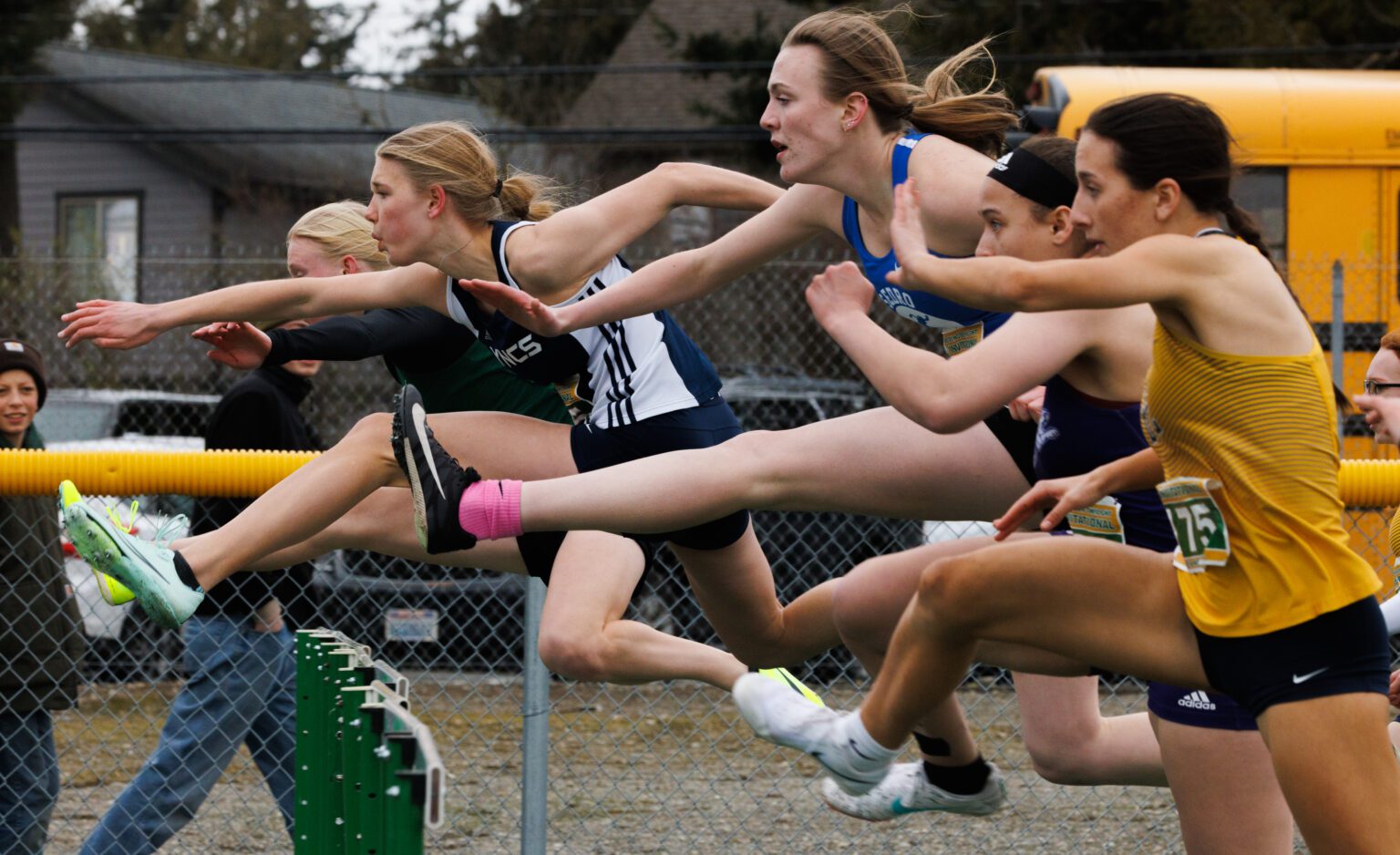 Lynden Christian's Avery Vanweerdhuizen leaps over hurdles as many other runners leap alongside.