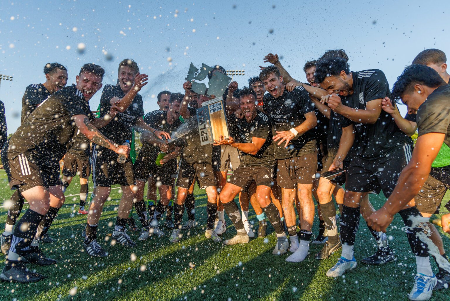 Players spray champagne as Bellingham United FC celebrates its 3-2 win over Washington Premier for the Evergreen Premier League championship at Orca Field on July 23.