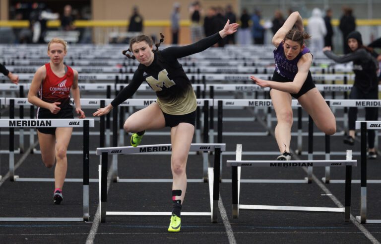 Meridian's Erica Stotts and Nooksack Valley's Emily Perry knock over their final hurdles but make it to the finish line March 31 at the Meridian-hosted Trojan Twilight Invitational.