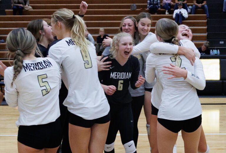 Players and coaches celebrate as Meridian beats Lynden 3-1 in sets (25-23