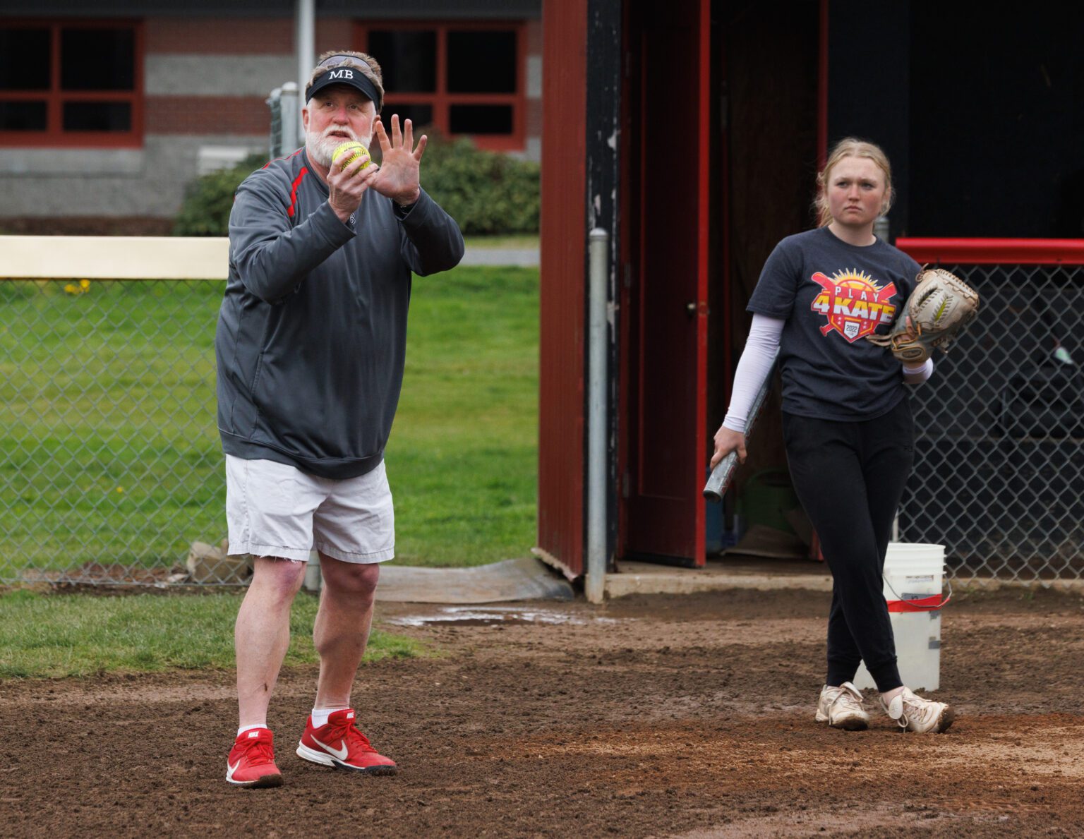 Mount Baker softball coach Ron Lepper demonstrates how to set up for the throw while catching the ball during practice.