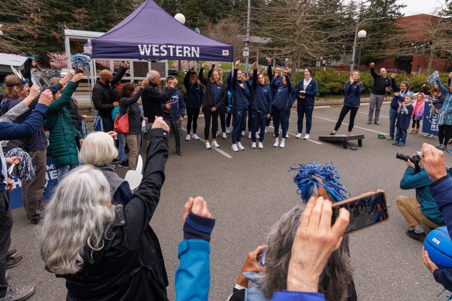 Fans raise an imaginary glass as they “toast” the Western Washington University women’s basketball team after their arrival home on March 26. The team finished in second place in the NCAA Division II women’s basketball national championship on Friday.