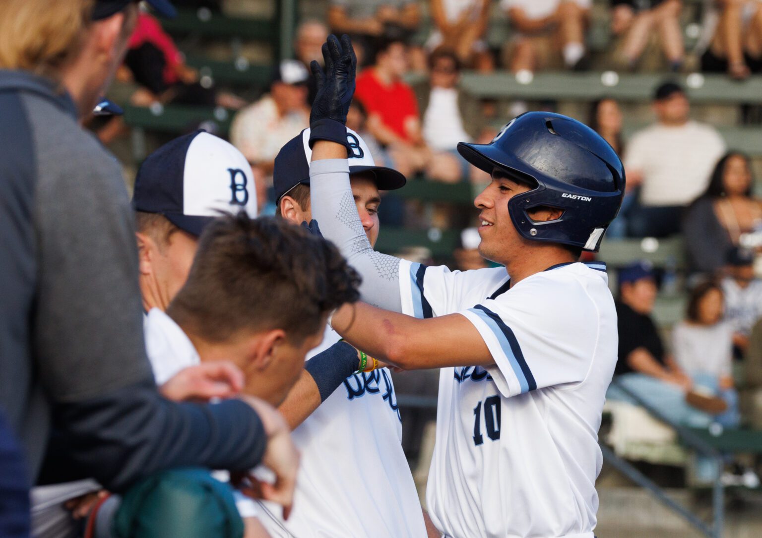 Christopher Campos high-fives teammates after scoring on a walk as the Bellingham Bells tie up the game 1-1 Thursday
