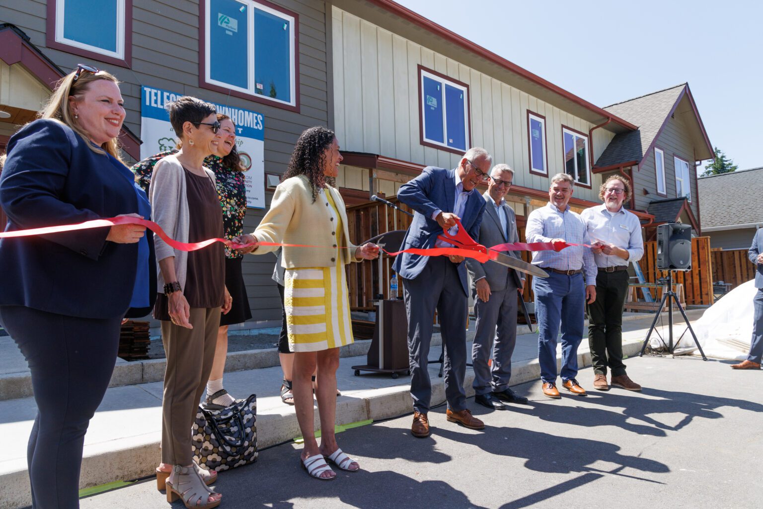 Gov. Jay Inslee cuts a ribbon at a ceremony for the Telegraph Townhomes
