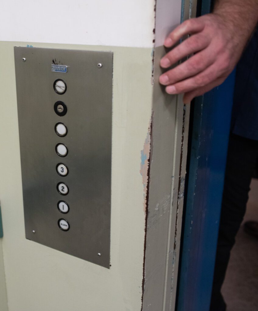 A man's hand reaches for elevator buttons in the jail.
