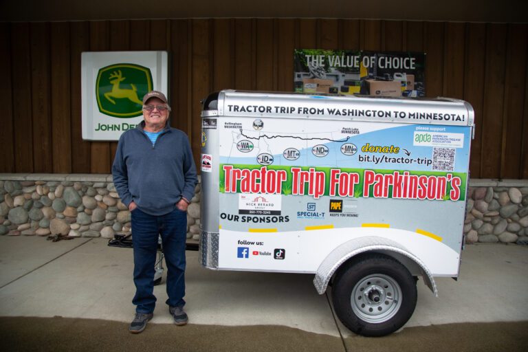 Mike Adkinson stands next to his trailer in April 2022. He pulled the trailer behind a John Deere tractor during a cross-country trip to raise money for Parkinson's disease in May 2022. This month