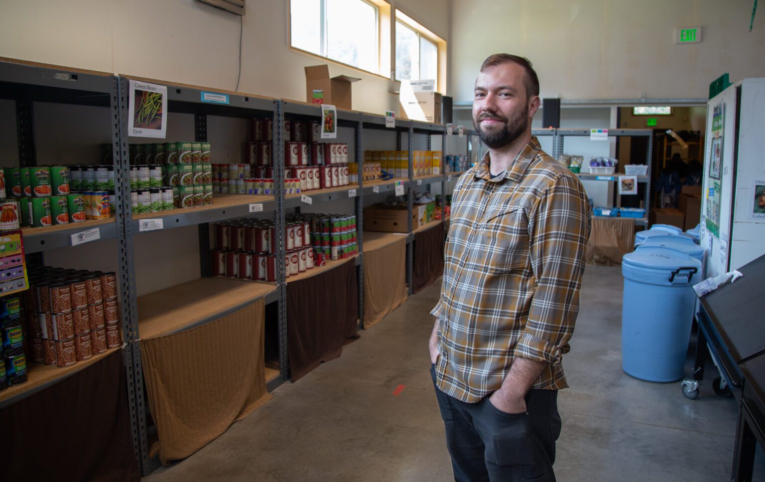 Sam Norris, the executive director of Foothills Food Bank. Norris, stands next to shelves of canned food.