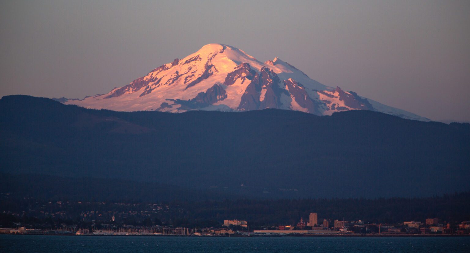 Mount Baker glows pink and looms over Bellingham as seen from Lummi Shore Road in July 2022. Bellingham's nearby hiking trails