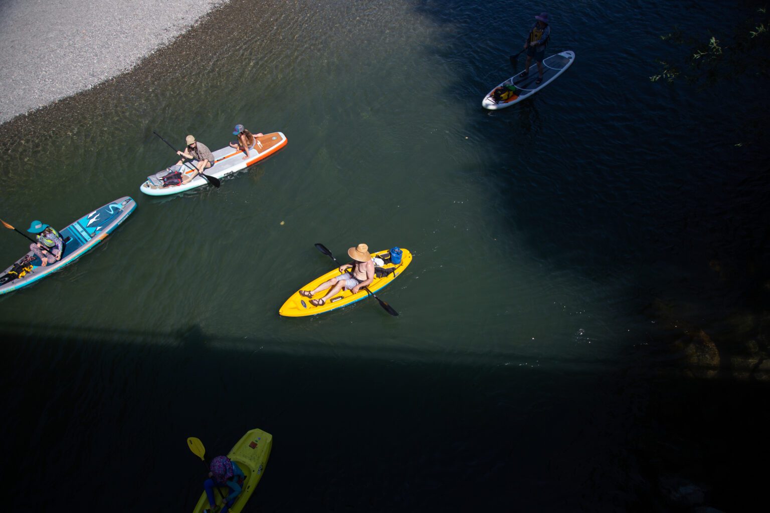 People float beneath the Acme Bridge on the South Fork Nooksack River on paddle boards and kayaks on July 28.