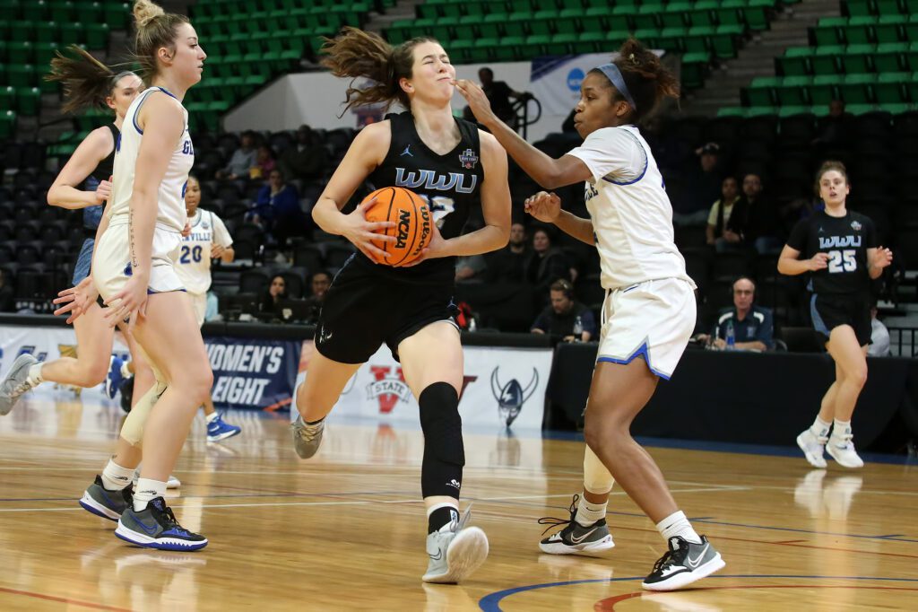 A basketball player being blocked by the other team as she runs inbetween them.