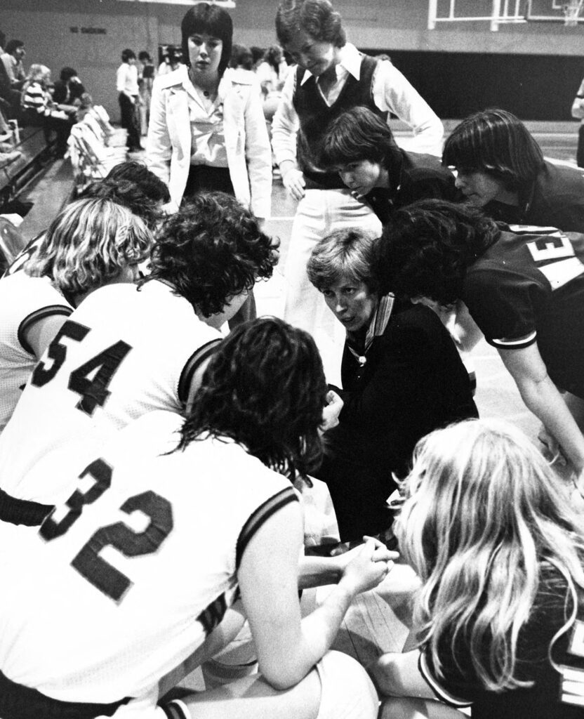 A female coach talks to a women's basketball team.