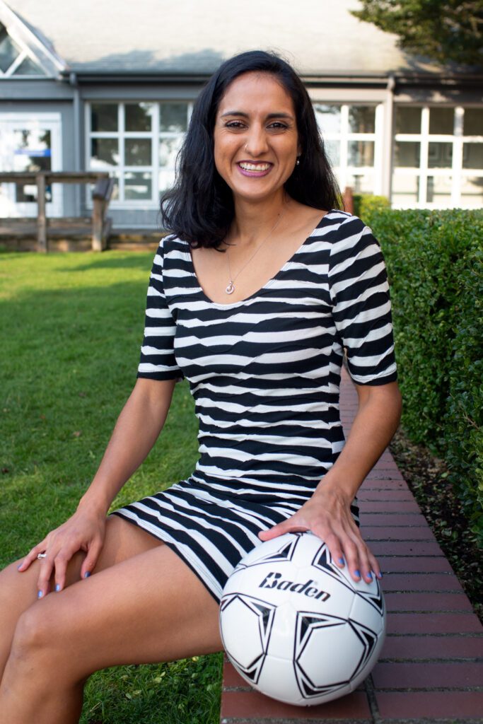Suneeta Eisenberg sitting down while holding a soccer ball.