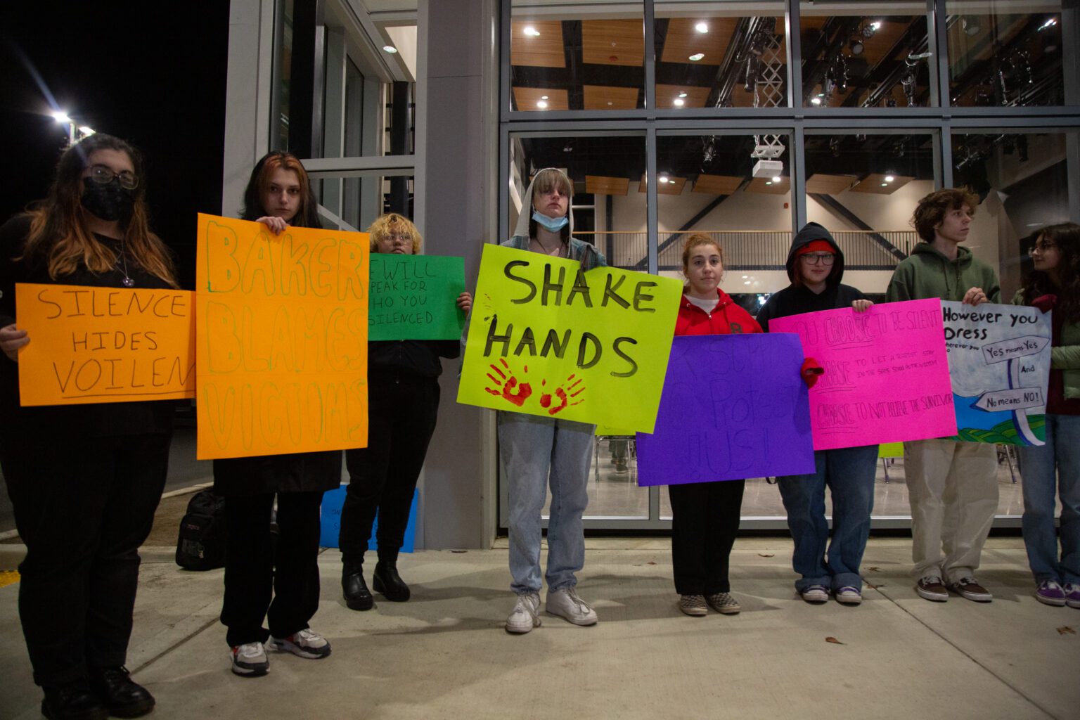 About two dozen students hold signs in protest before a school board meeting at Options High School on Dec. 14. The signs condemn Bellingham Public Schools for the alleged failure of three assistant principals to report the sexual assaults of a Squalicum High School student.