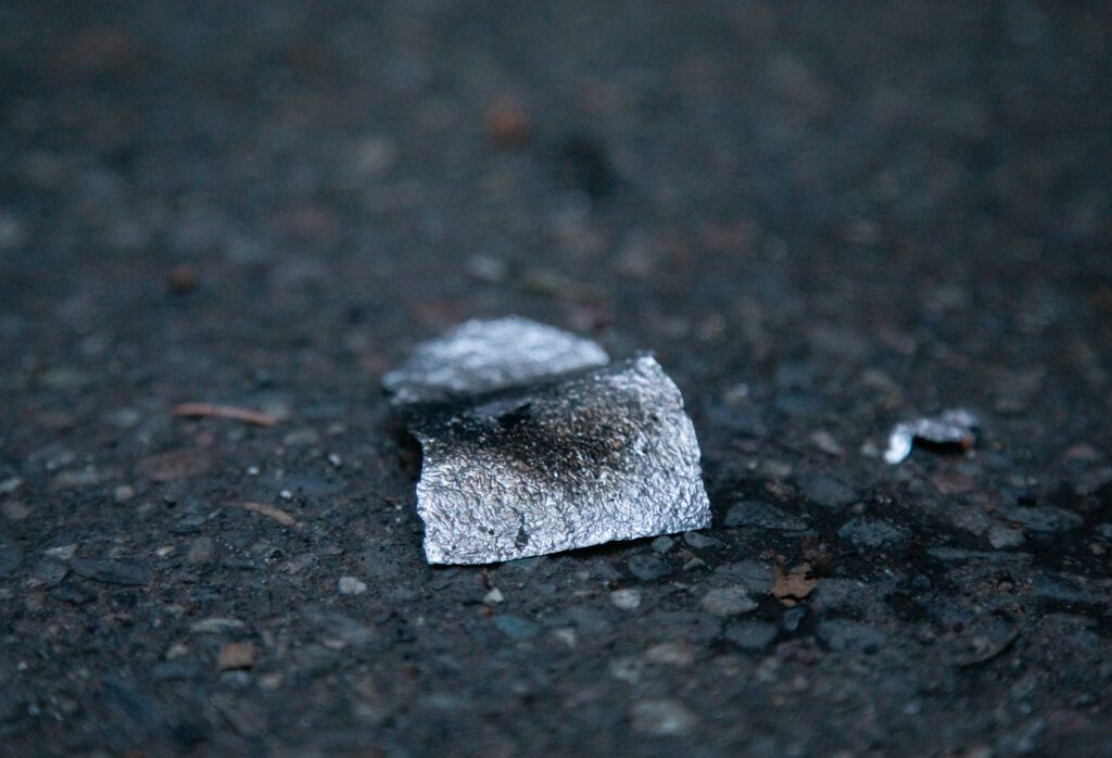 A burned piece of tinfoil sits on cement.