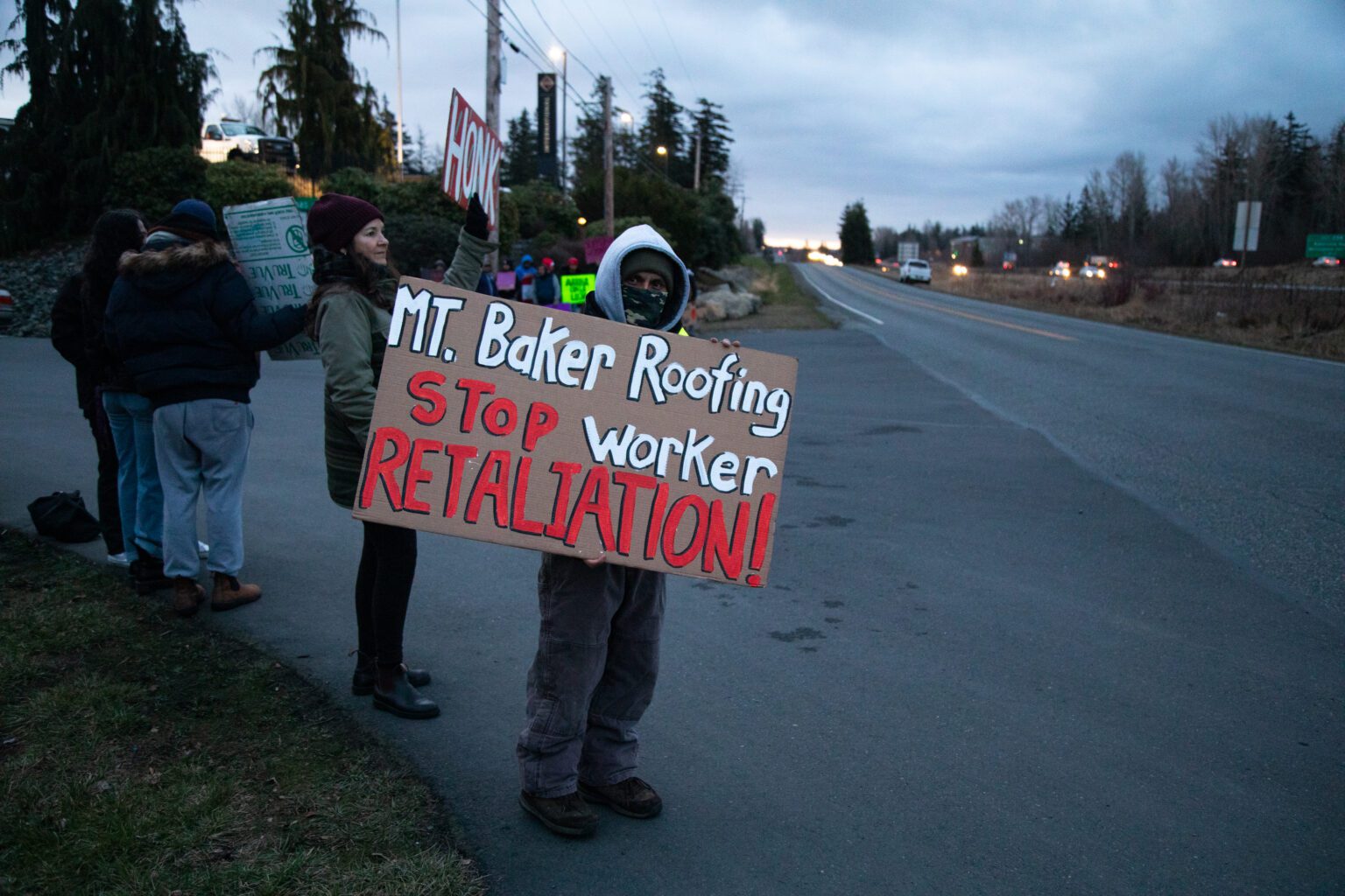A Mt. Baker Roofing employee holds a sign calling for the end to worker retaliation Feb. 14. A work stoppage occurred following allegations of the company failing to provide bathrooms