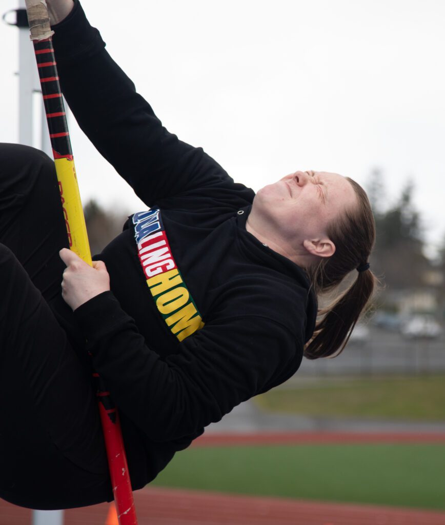 Morgan Annable demonstrates a drill during practice with her eyes shut as she pole vaults with the red, black, and yellow pole.