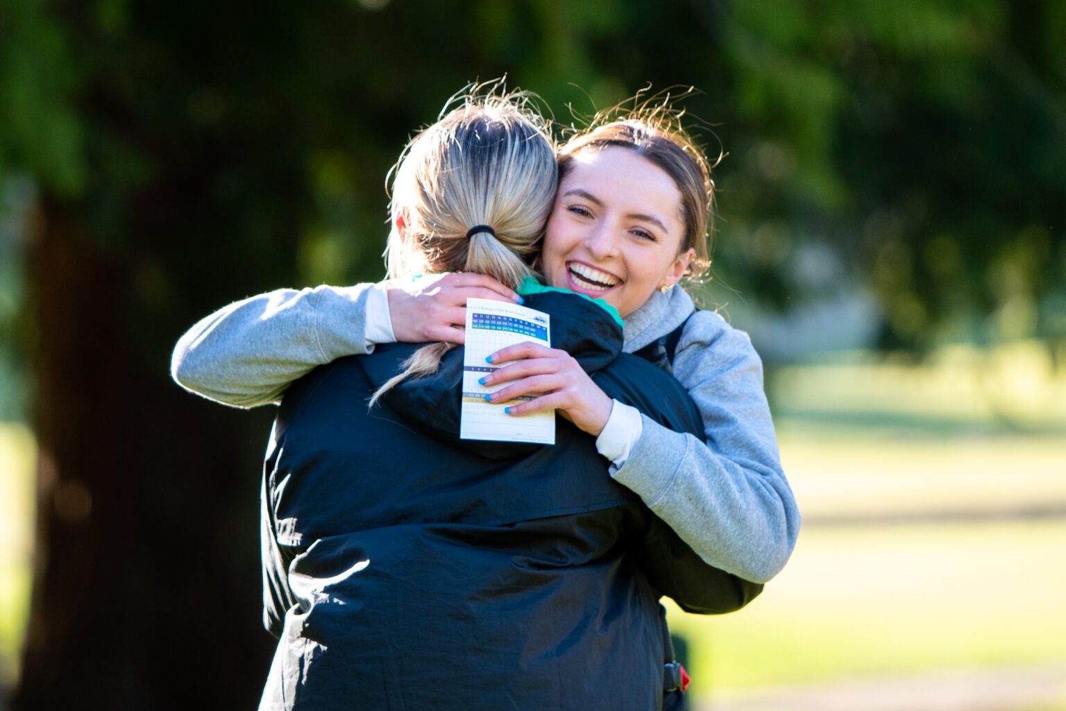 Sehome's Hannah Hochsprung hugs Lynden's Kinsley Rector with a score pamphlet in hand.