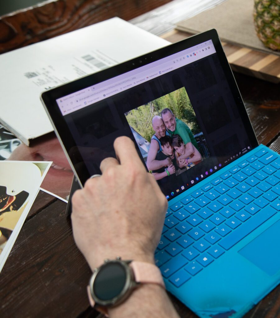 Kevin Coleman shows a family photo of him, his husband, and their adopted sons on a laptop.