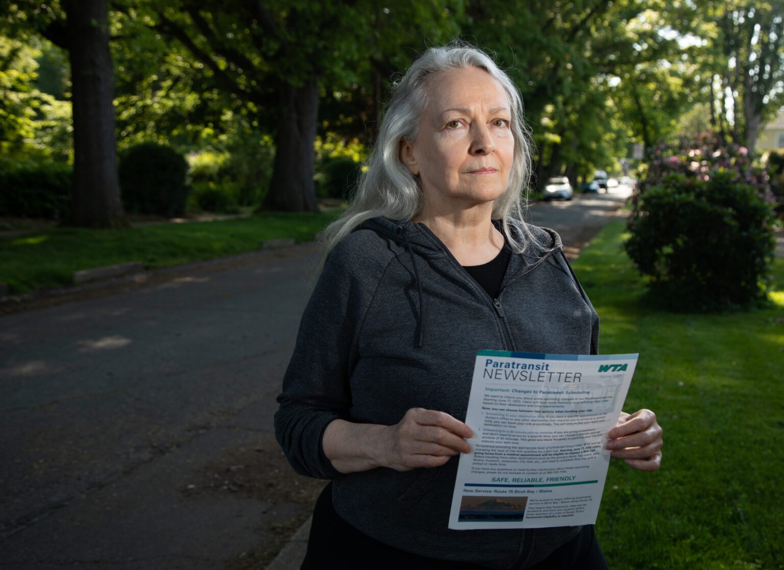 Linda Joy De Long holds a newsletter from Whatcom Transportation Authority about changes that would no longer allow paratransit users to call for a pickup after finishing their errands.