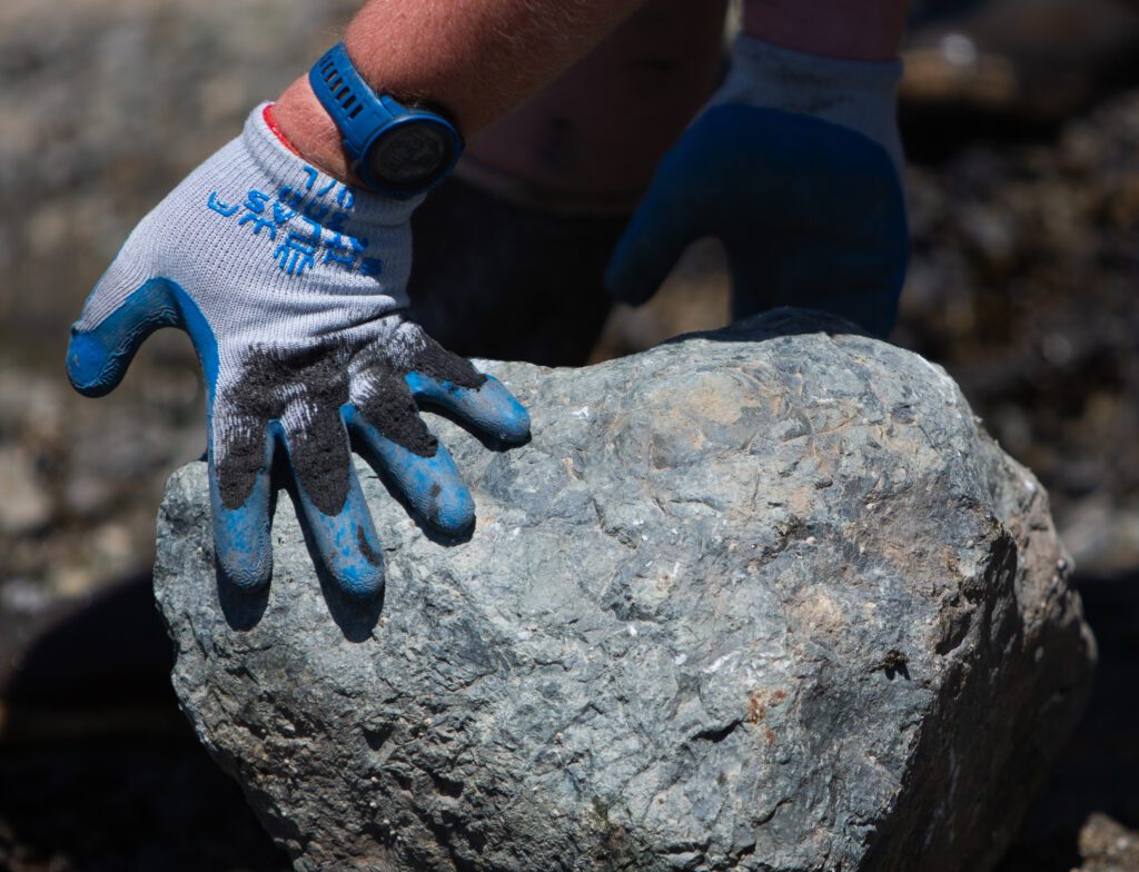 A pair of gloved hands rolling a rock.