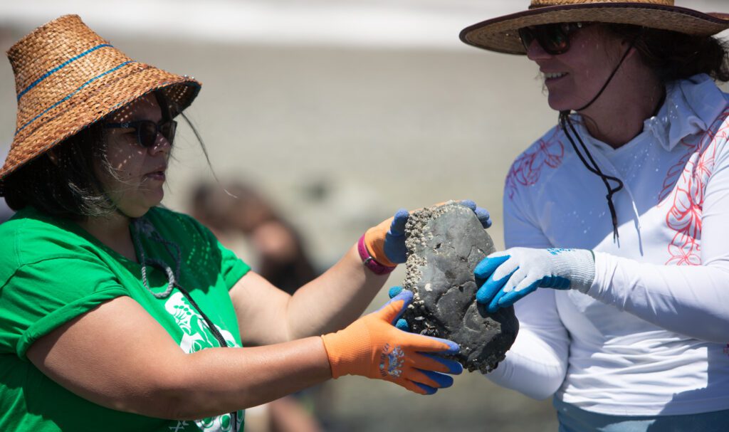 Azure Bouré, left, of the Suquamish Tribe takes a rock from Emma Norman, a Northwest Indian College professor.