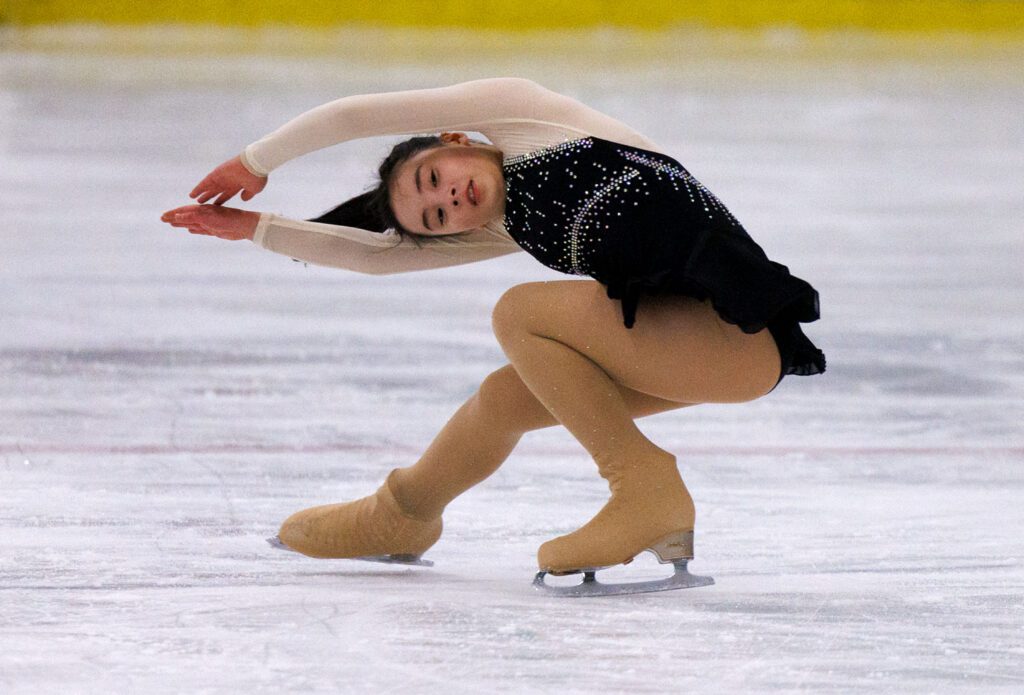 Clara Rogers of the Bellingham Figure Skate Club practices as she leans down with her arms pointed.