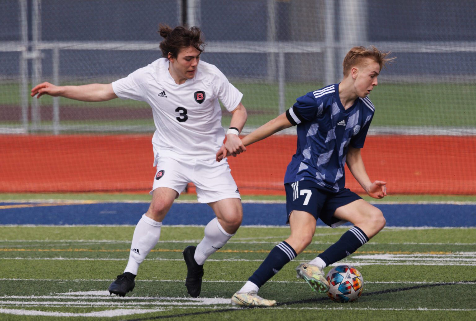 Bellingham's Lorenzo Pellecchia tries to hold back Squalicum’s Xander Koenig March 25 as the Storm beat the Bayhawks 2-0 at Squalicum High School.