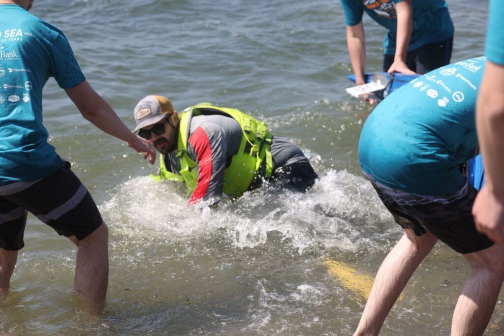 Kyle Hager falls out of his kayak as he lands at the finish line.