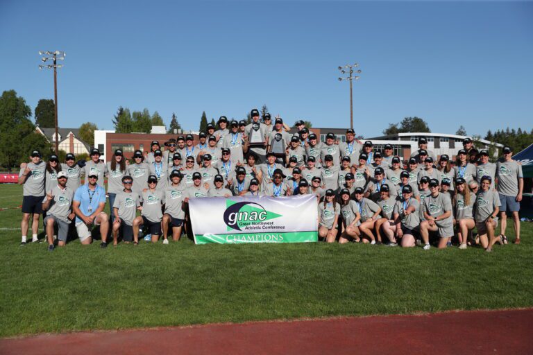 Western Washington University men's and women's track and field athletes gather with their Great Northwest Athletic Conference trophies and banner after sweeping the outdoor season conference titles May 13 in Monmouth