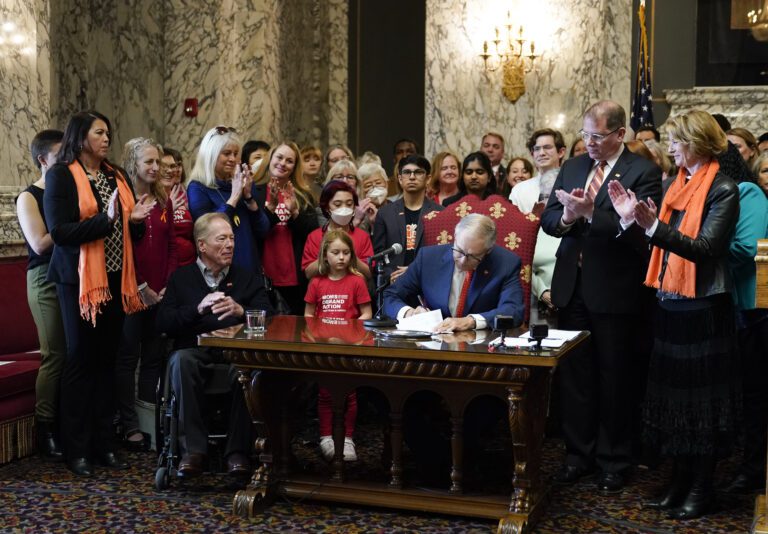 Washington Gov. Jay Inslee signs House Bill 1240 April 25 at the Capitol in Olympia
