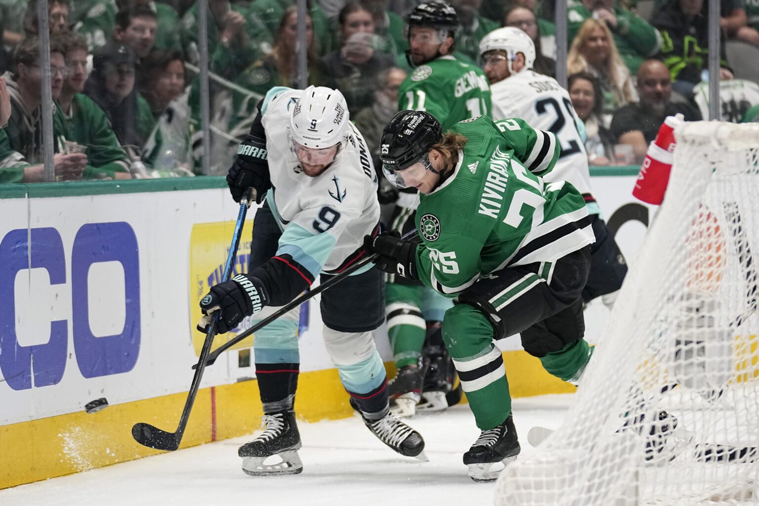 Seattle Kraken center Ryan Donato (9) clears the puck from behind the net under pressure from Dallas Stars left wing Joel Kiviranta (25) in the first period of Game 7 of an NHL hockey Stanley Cup second-round playoff series
