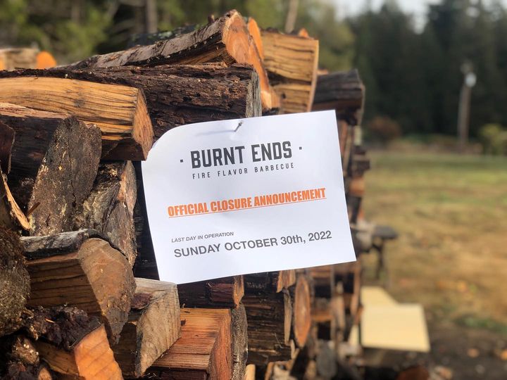 Stacks of cut wood with a white paper pinned to the log announcing the closure of Burnt Ends.