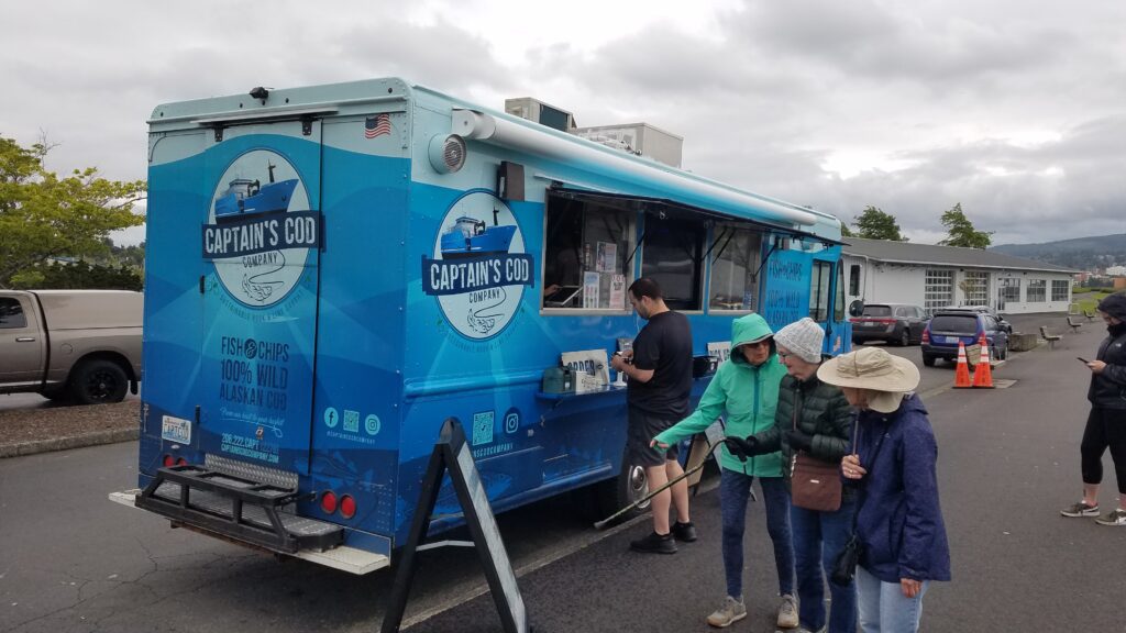 The Captain's Cod's seafood's bright blue truck as customers buy and point at the menu propped up next to the truck.