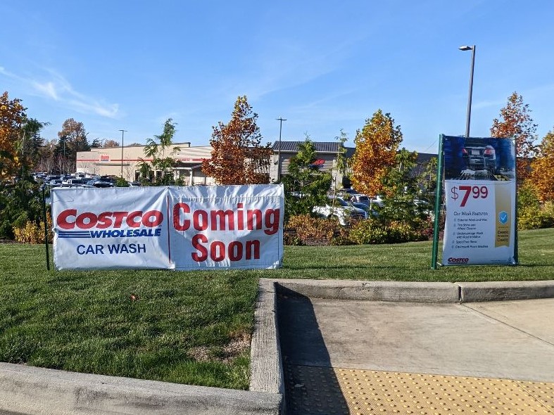 A sign outside Costco in Bellingham announcing the soon-to-open car wash propped up on the grass.
