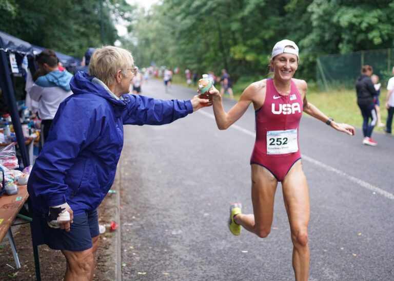 Bellingham's Courtney Olsen grabs a bottle of tea from team lead Lin Gentling while competing for the U.S. women in the International Association of Ultrarunners 100K World Championship in Bernau