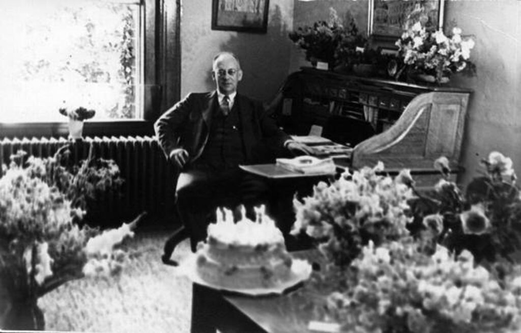 A black and white photo of Charles Fisher, in his office, on the occasion of his 15th anniversary as college president in 1938.