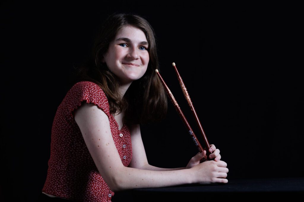 A photo of Hannah Nyland holding drummer sticks.