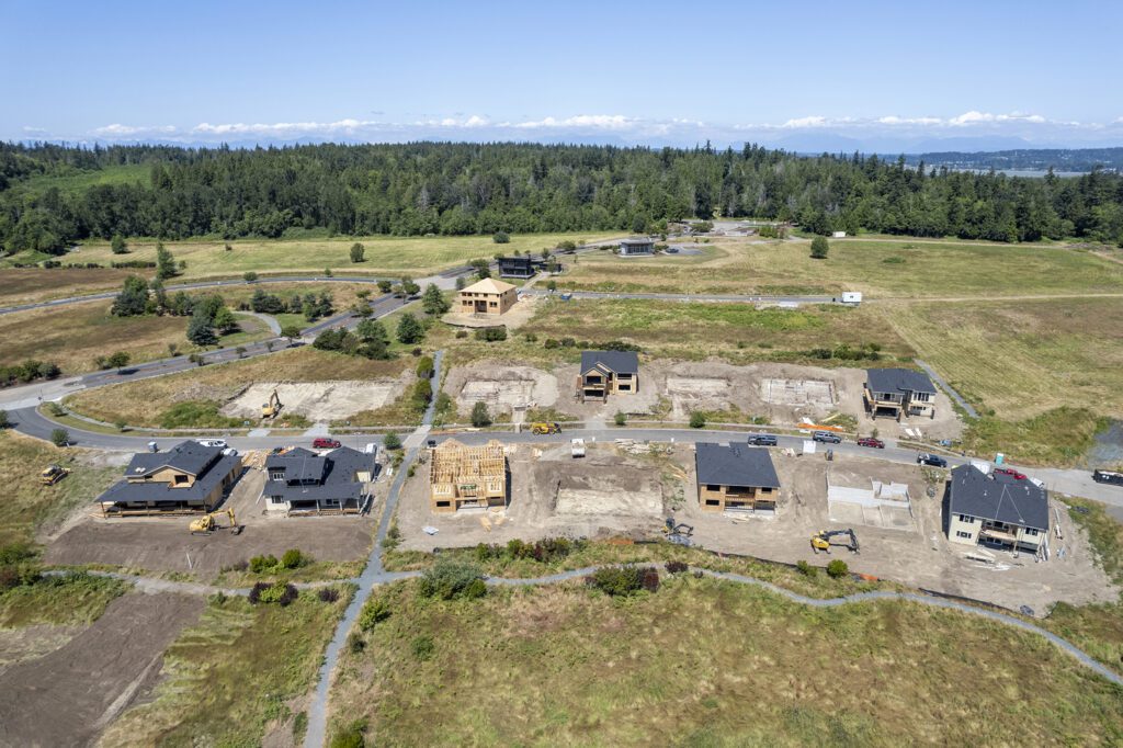 New homes under construction at the Horizon community in Blaine surrounded by flat grassy land surrounded by forests.