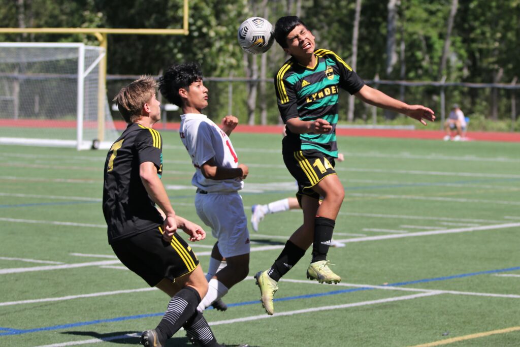 Lynden's Victor Huaracha heads a ball as he winces in bain as other players brace for the ball behind him.