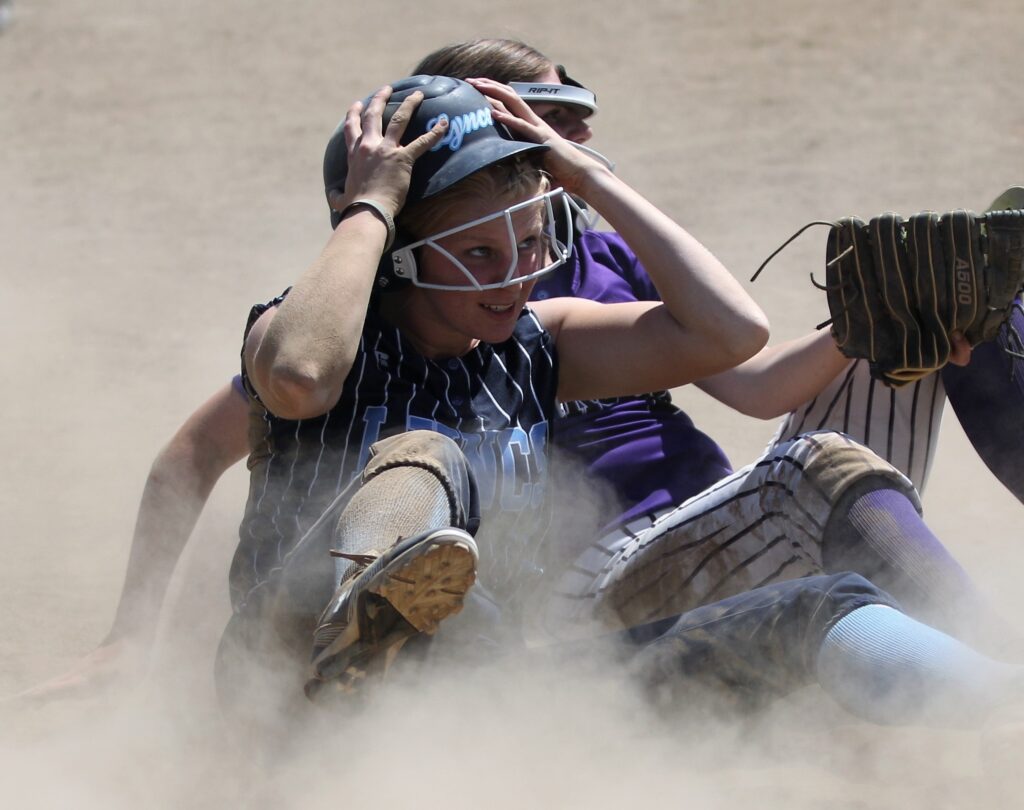 Lynden Christian's Addison DeJong straightens out her helmet after colliding with Nooksack Valley's Grace DeHoog amidst the cloud of dust settling from the collision.