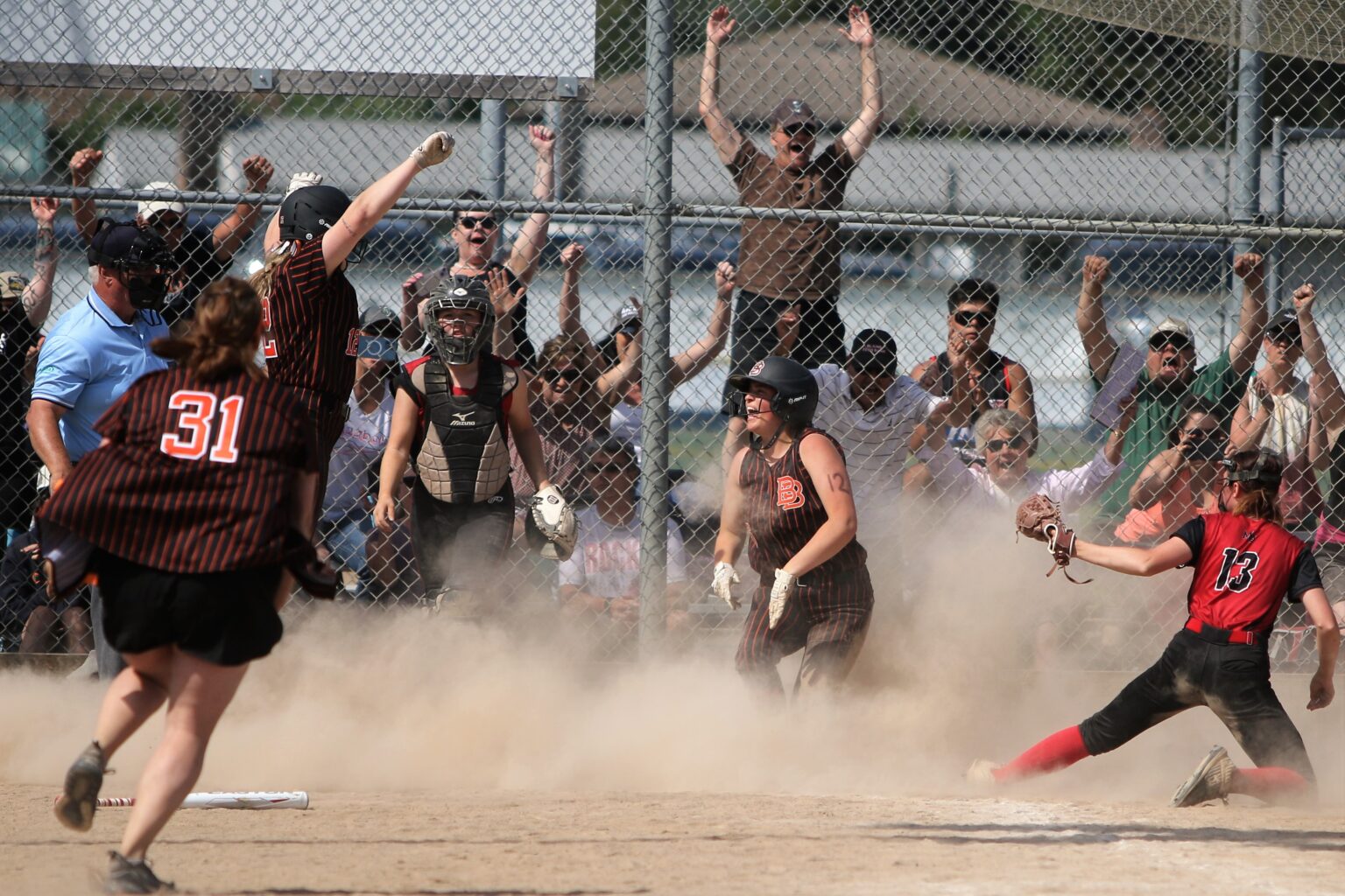 The crowd cheers from behind the chain-linked fence as Blaine's Shaylie Daniels slides home leaving behind a dust trail as her teammates jump and celebrate.