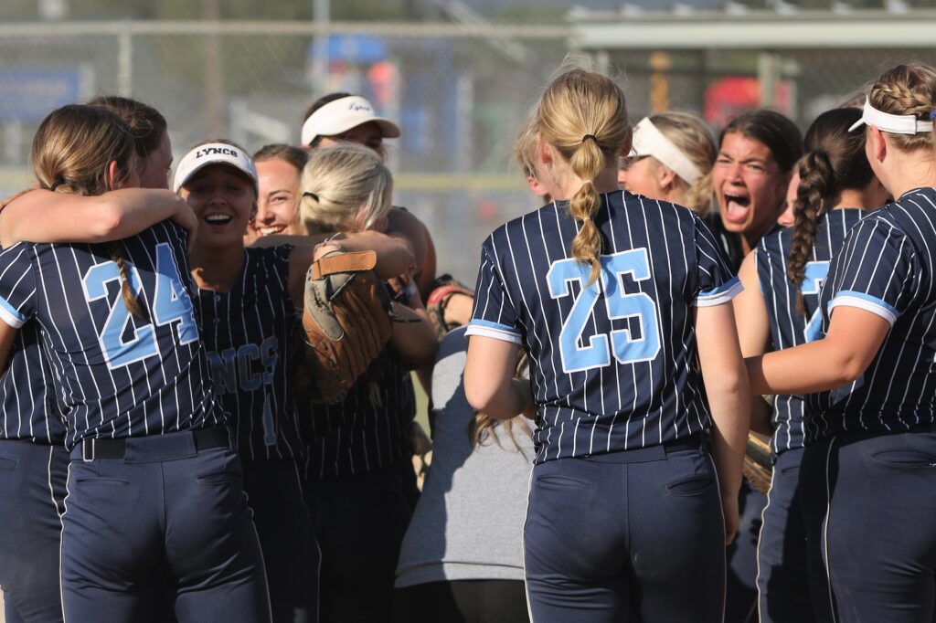 Lynden Christian celebrating as they hug with big smiles in a crowded huddle.