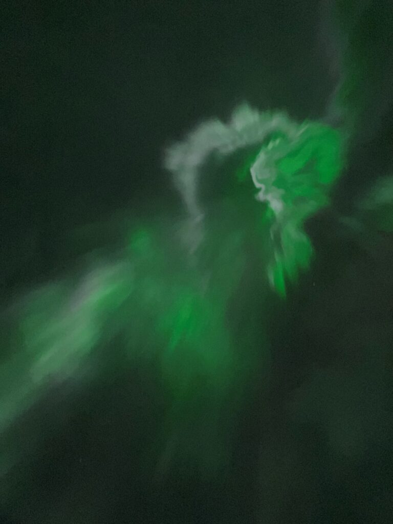 A smoke-like photo of the northern lights in the dark sky.