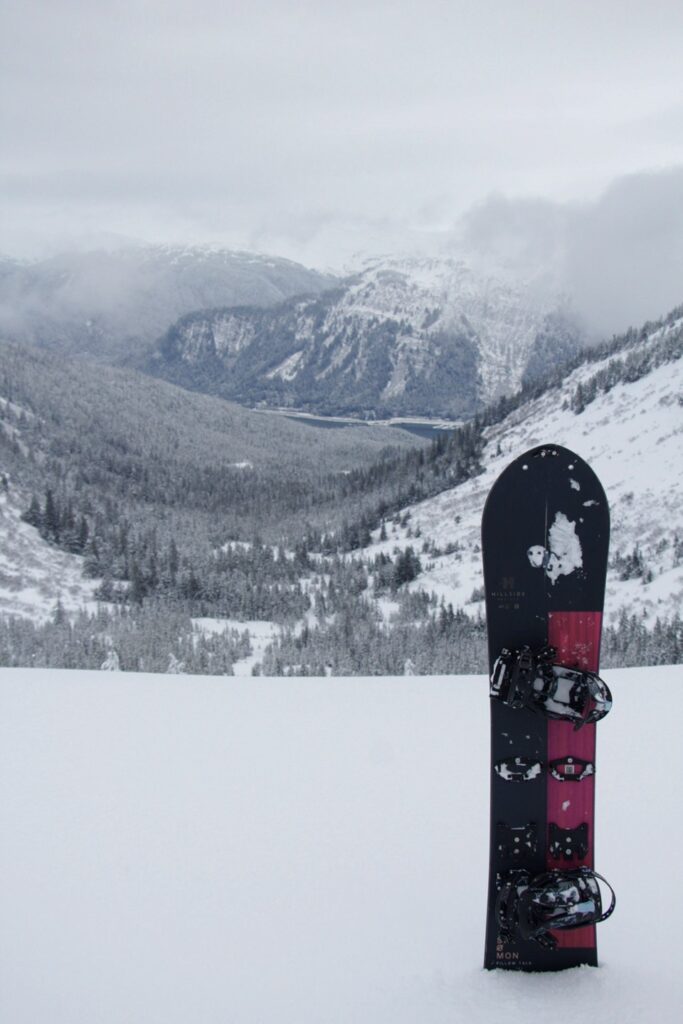 CDN outdoors columnist Kayla Heidenreich's black and red snowboard stands up in the snow in the Tongass National Forest.
