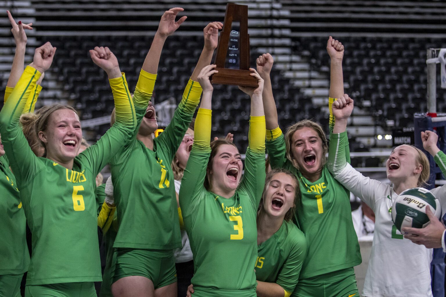 Lynden volleyball players celebrate and lift the fifth-place trophy after defeating Washington of Tacoma at the 2A state tournament in Yakima on Nov. 19.