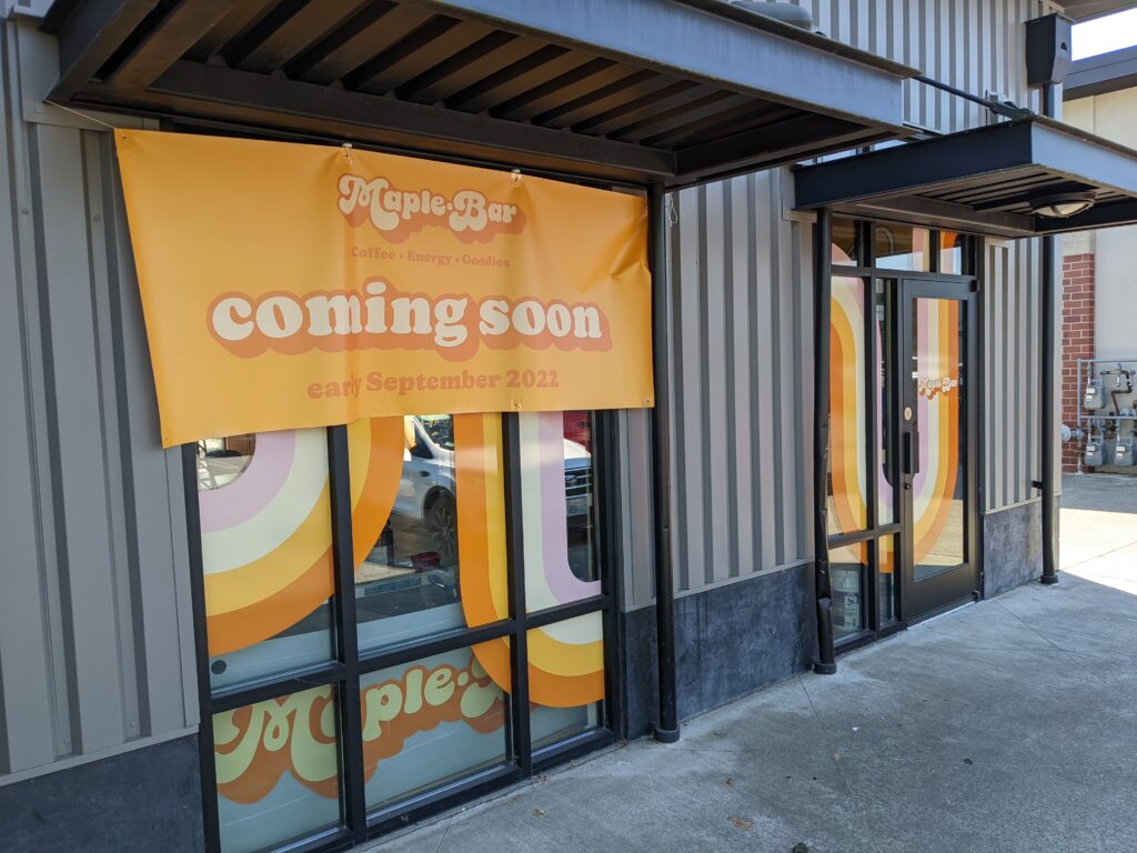 The storefront of Maple Bar with a bright orange banner announcing the launch date of their store.
