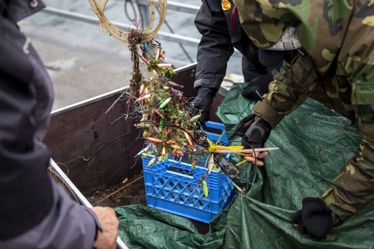 A basket full of lures and other finds is examined during an underwater scuba maintenance event April 2 at the Edmonds Fishing Pier in Edmonds