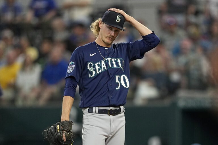 Seattle Mariners starting pitcher Bryce Miller adjusts his cap as he stands on the mound.