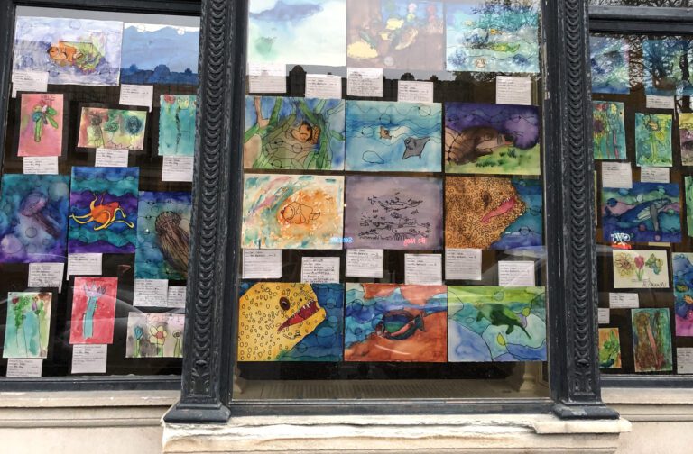 Children's art fills the windows of downtown businesses in May for Art Education Month.