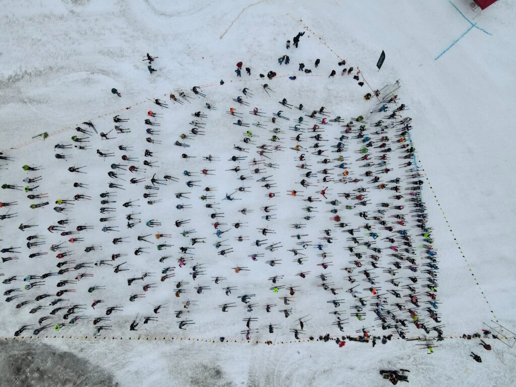 An aerial view of a large group of skiers waiting at the starting line.